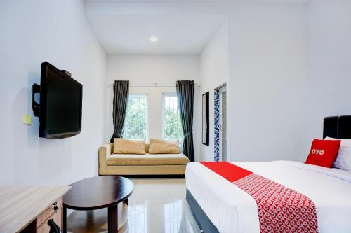 a bedroom with a bed and a tv and a couch at Collection O Almasarra Residence Near Ring Road Medan in Medan