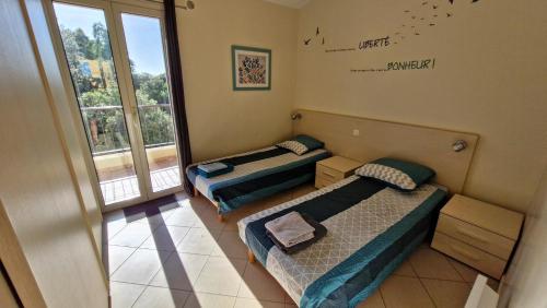deux lits dans une chambre avec une fenêtre dans l'établissement Duplex 4-6 p, Terrasses, Piscine, climatisé, Lozari, Corse, à Belgodère