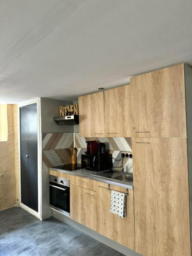 une cuisine avec des armoires en bois et un four à plaques de cuisson dans l'établissement Love Queen SPA DÉTENTE, à Blois