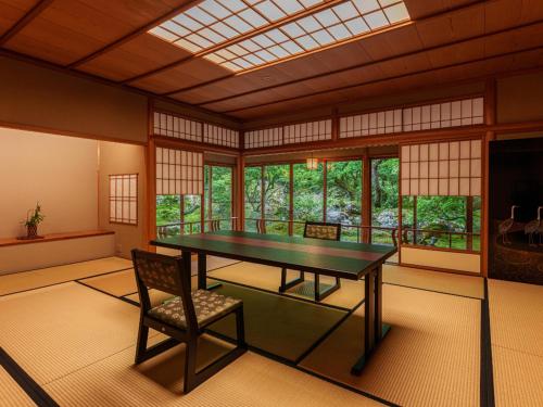 a room with a table and a chair and windows at 旅亭 半水盧 in Unzen
