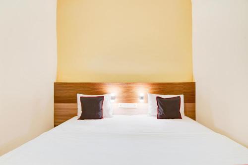 a bedroom with a white bed with two pillows at Capital O Pusat Kota Pekanbaru Near Mall Living World Formerly Radja Homestay in Pekanbaru