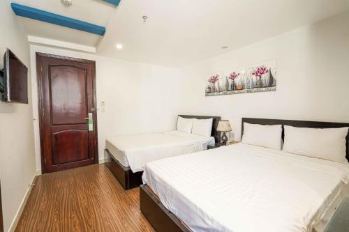 a bedroom with two beds and a door at Arima Hotel Nha Trang Beach by HC Group in Nha Trang