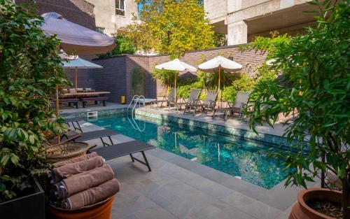 a swimming pool with tables and chairs and umbrellas at Communal Hotel Kutaisi in Kutaisi