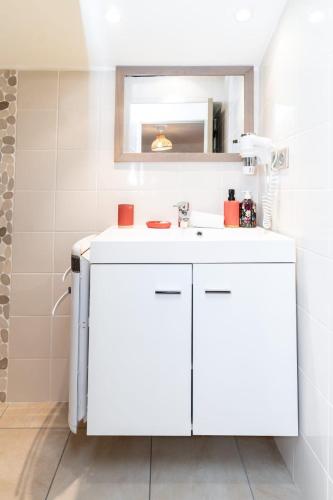 une salle de bain avec un lavabo blanc et un miroir dans l'établissement La Maison dans les remparts, à Sainte-Eulalie-de-Cernon