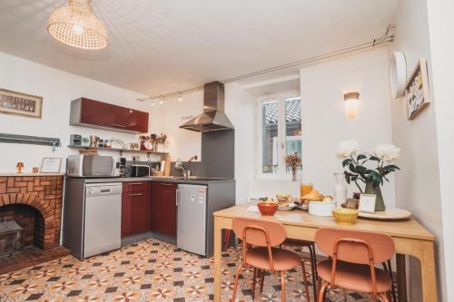 una cucina con tavolo e camino di La Maison dans les remparts a Sainte-Eulalie-de-Cernon