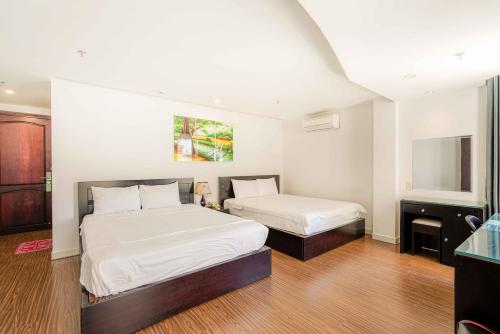 a bedroom with two beds and a mirror at Arima Hotel Nha Trang Beach by HC Group in Nha Trang
