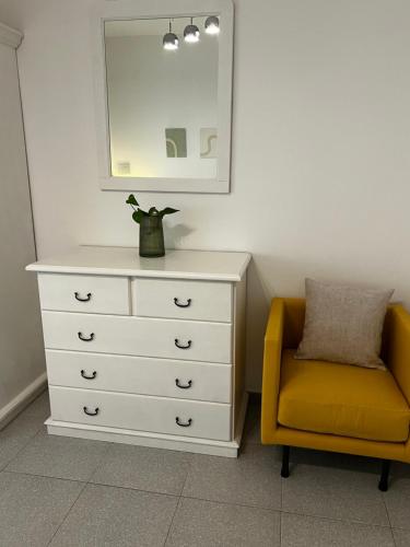 a white dresser with a yellow chair and a mirror at Casa Curiosa in Porto Torres