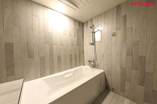 a white bath tub in a bathroom with tiled walls at Ignis Hotel busan sports complex branch in Busan