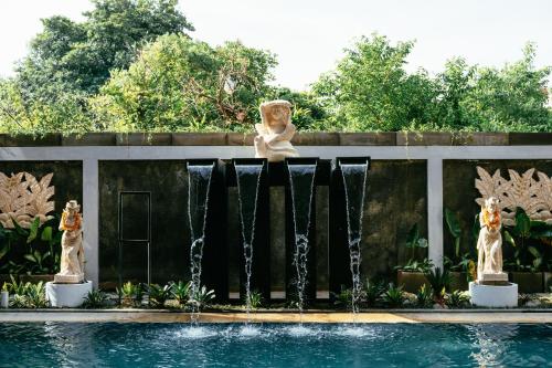 a statue of a woman sitting on a fence next to a fountain at Nadi Hotel Legian in Legian