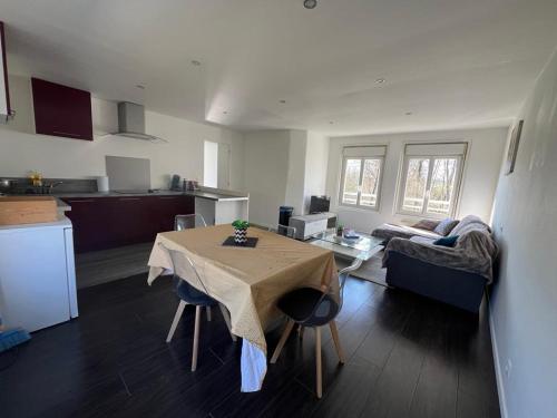 a kitchen and living room with a table and a couch at Appartement calme et paisible au bord de la rivière in Ernée