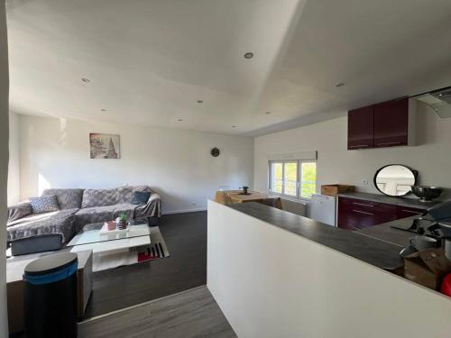 a kitchen and a living room with a couch at Appartement calme et paisible au bord de la rivière in Ernée