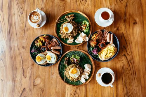 a wooden table with plates of food and cups of coffee at Nadi Hotel Legian in Legian