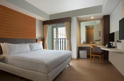a bedroom with a bed and a desk and a kitchen at Vega Hotel Gading Serpong in Serpong