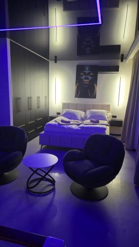a bedroom with two chairs and a bed with purple lighting at Apartament dla dwojga z jacuzzi na wyłączność in Świecie