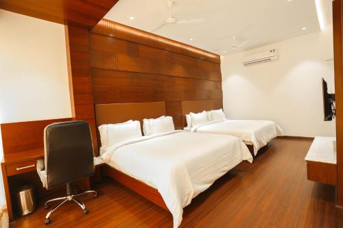 a bedroom with two beds and a desk and a chair at Hotel Lakshmi Towers in Kāngayam