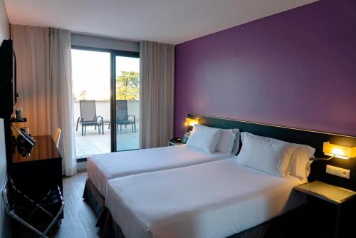 a bedroom with a large bed with a purple wall at Sercotel Córdoba Medina Azahara in Córdoba