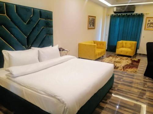 a bedroom with a large bed and two yellow chairs at Royal Mansion Hotel in Multan