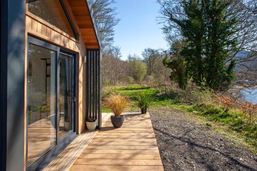 a house with a wooden porch with potted plants on it at Appin Holiday Homes -Caravans, Lodges, Shepherds Hut and Train Carriage stays in Appin