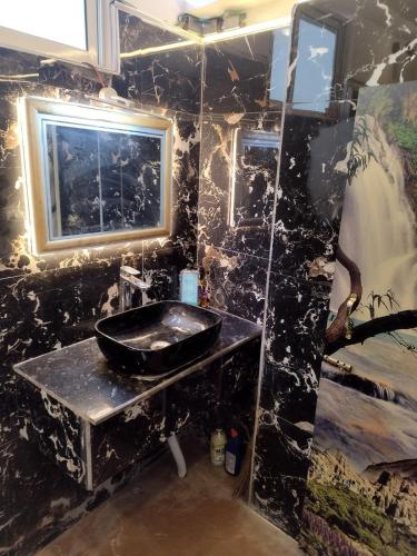 a black bathroom with a sink and a window at Mig's Suite in Darjeeling