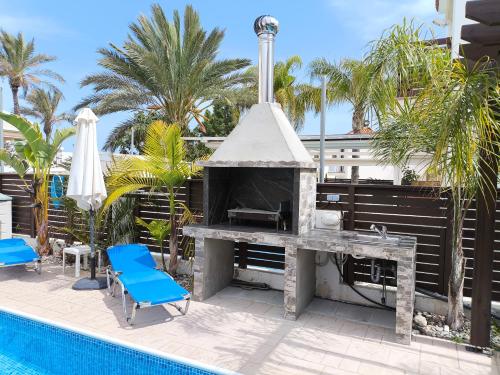 a fireplace next to a swimming pool with a blue chair at Villa Casa Palmera in Paralimni