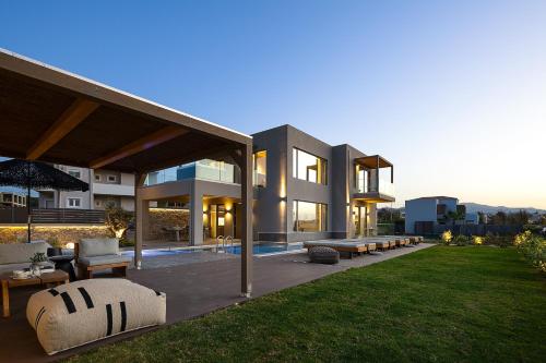 a large house with a patio and a lawn at Villa Aya - Coastal Villa, Minimalist Elegance by etouri in Stavromenos