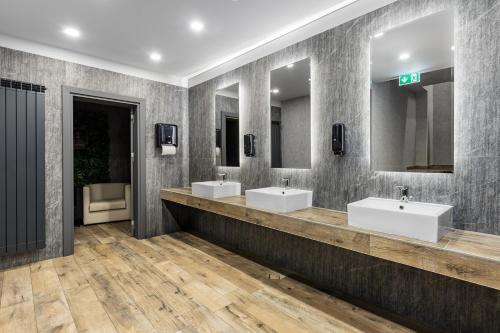 a bathroom with three sinks and two mirrors at Jitomir Hotel in Montana