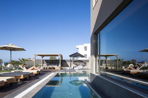 a hotel swimming pool with people laying on lounge chairs at Villa Aya - Coastal Villa, Minimalist Elegance by etouri in Stavromenos