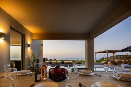 a dining table with wine glasses and a view of a patio at Villa Aya - Coastal Villa, Minimalist Elegance by etouri in Stavromenos