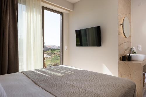 a bedroom with a bed and a window with a television at Villa Aya - Coastal Villa, Minimalist Elegance by etouri in Stavromenos
