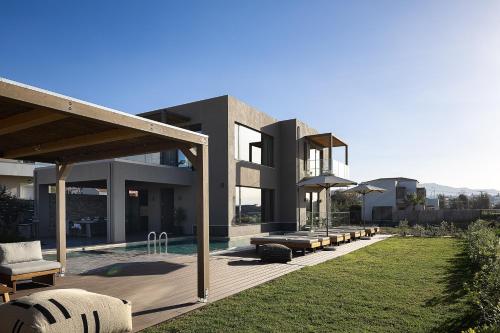 a house with a pool and a yard with benches at Villa Aya - Coastal Villa, Minimalist Elegance by etouri in Stavromenos