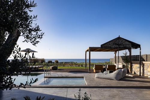 a pavilion with a table and chairs and the ocean at Villa Aya - Coastal Villa, Minimalist Elegance by etouri in Stavromenos