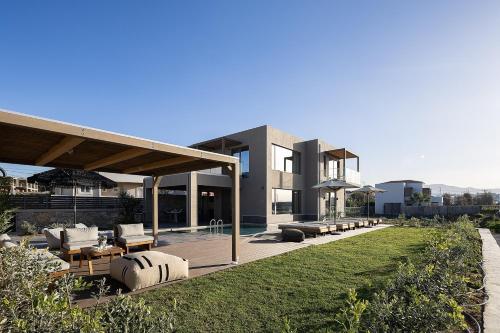 a house with a patio with couches and a pool at Villa Aya - Coastal Villa, Minimalist Elegance by etouri in Stavromenos
