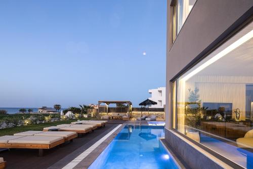 a hotel with a swimming pool and a building at Villa Aya - Coastal Villa, Minimalist Elegance by etouri in Stavromenos