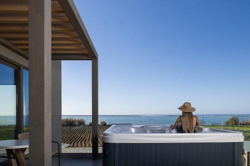 a woman sitting in a bath tub next to the ocean at Villa Aya - Coastal Villa, Minimalist Elegance by etouri in Stavromenos