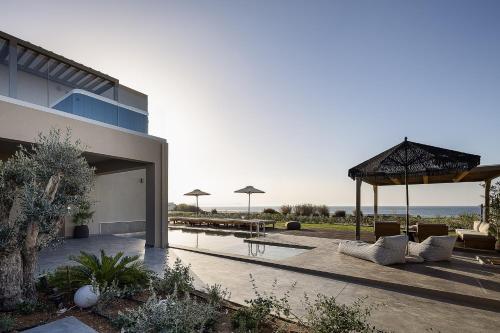 a house with a patio with couches and a table at Villa Aya - Coastal Villa, Minimalist Elegance by etouri in Stavromenos