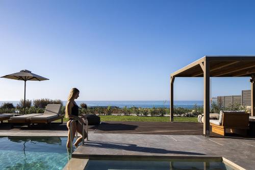 a woman is standing next to a swimming pool at Villa Aya - Coastal Villa, Minimalist Elegance by etouri in Stavromenos