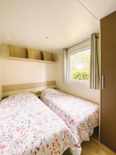 two beds in a small bedroom with a window at Camping maeva Escapades de la Gères in Surgères