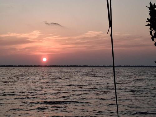 a sunset over a body of water with a boat at Suzukis lagoon front in Katunayake