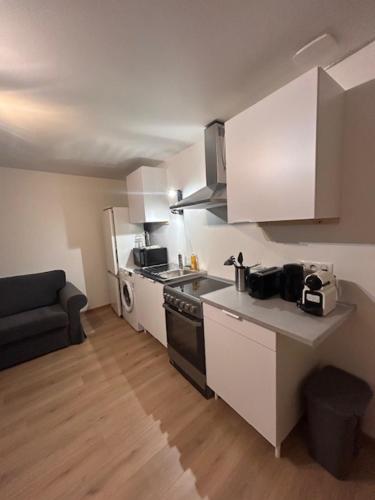 - une cuisine avec des placards blancs et une cuisinière noire dans l'établissement Le Premeaux, au cœur des vignes, à Prémeaux