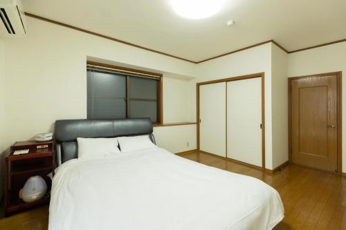 a bedroom with a large white bed and a window at 緑翠-Ryokusui- in Fukuoka