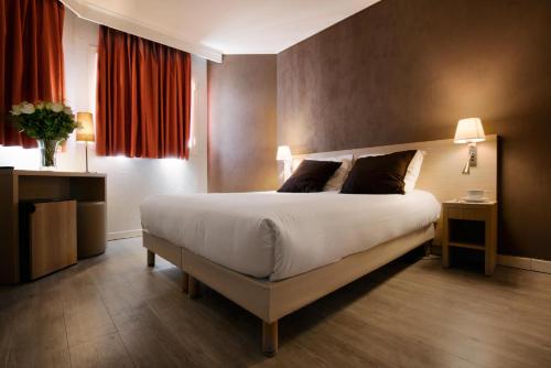 a bedroom with a large bed with two pillows at Hôtel de l'Étoile in Antibes