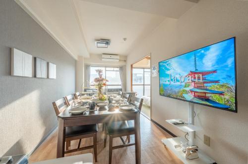 a dining room with a table with chairs and a tv at Newly opened Hotel 7 京セラドーム徒歩10分 道頓堀 関西空港 大阪城 海遊館直行 USJ1回乗換 出張 Family friendly Free parking 15 minutes by car to USJ in Osaka