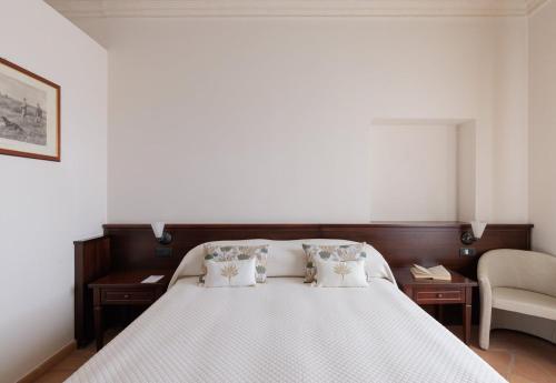 a bedroom with a bed with two tables and a chair at Hotel San Claudio in Corridonia