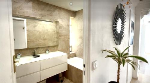 La salle de bains est pourvue d'un lavabo, d'un miroir et d'une plante. dans l'établissement Cannes appartement à louer, à Cannes