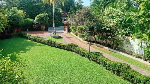 a garden with green grass and a fence at Rockery Villa Ayurveda in Bentota