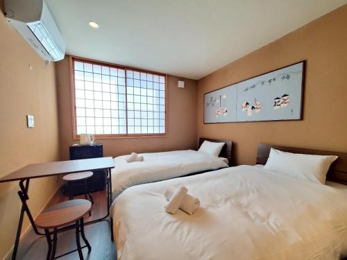 Una habitación de hotel con dos camas, un escritorio y una mesa. en The Bonsai Kiyomizu, en Kioto