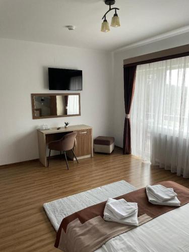 a bedroom with a bed and a desk and a window at Villa Prestige in Sovata