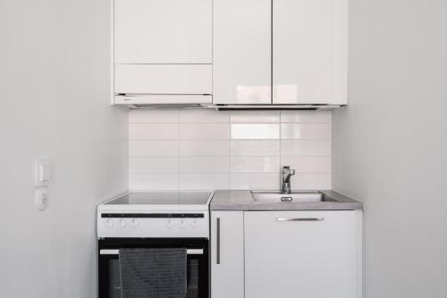 Una cocina blanca con fregadero y estufa. en Stylish Studio Apartment with Excellent Location, en Helsinki