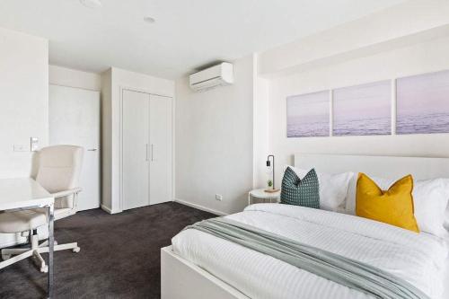 a white bedroom with a bed and a desk at Chic 2BR Loft Near Melbourne Central Free Parking in Melbourne