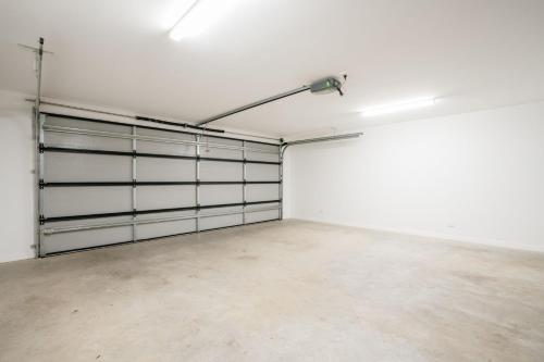 an empty garage with white walls and metal garage doors at Tree Top Haven Itas in Kings Meadows